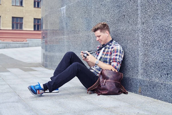 Heerlijke man in hoofdtelefoon foto's kijken zijn camera — Stockfoto