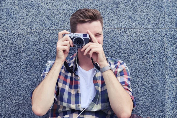 Joven fotógrafo sentado y tomando fotos con ca vintage —  Fotos de Stock