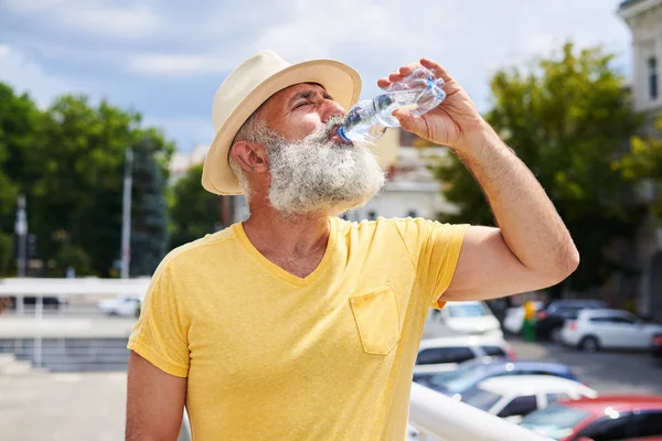 Uomo barbuto assetato che beve acqua nella giornata calda — Foto Stock