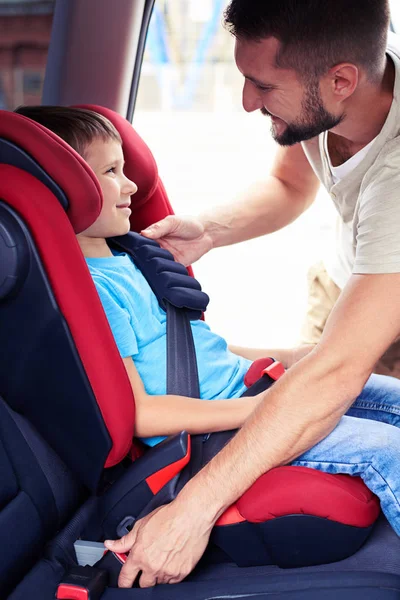 Sorrindo filho em assento de carro infantil sendo colocado na parte de trás do carro por carin — Fotografia de Stock