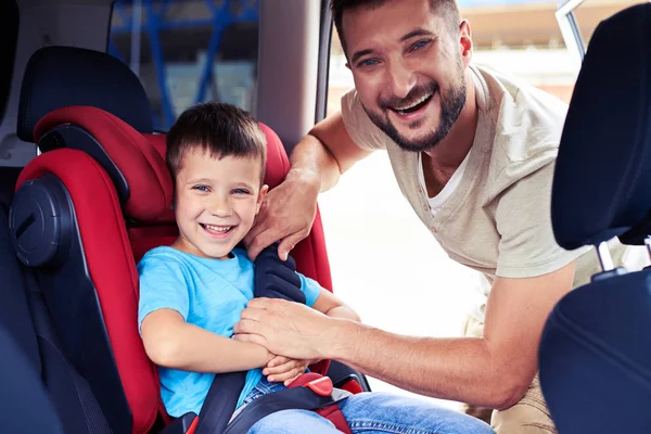 Happy father helps his son to fasten belt on car seat — Stock Photo, Image