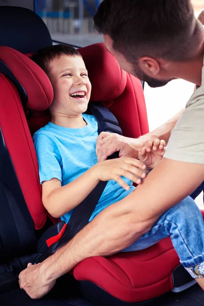 Mały chłopiec uśmiecha się, podczas gdy jego ojciec pozwala zapiąć pas na samochód s — Zdjęcie stockowe