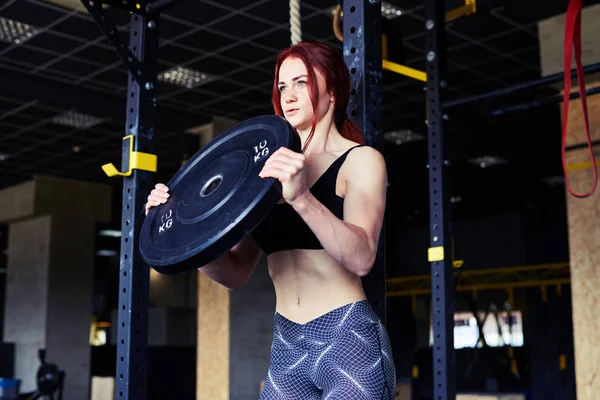 Aantrekkelijk meisje werkt met barbell in sportschool — Stockfoto