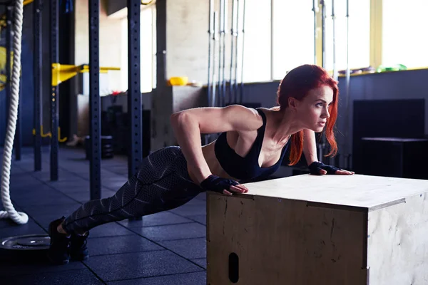 Junge schlanke Fitness-Frau macht Liegestütze auf Holzkiste — Stockfoto