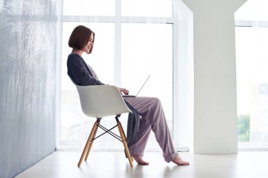 Koltukta oturan ve içinde laptop sörf gülümseyen kadın