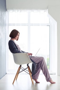 Kız koltukta oturan ve içinde laptop sörf pijama
