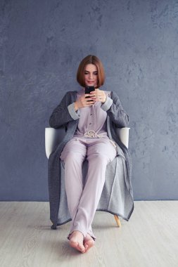 Smartphone kullanarak ve koltukta oturan rahat kadın