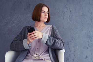 Kadın, bir yere bakarak ve cep telefonuyla kare