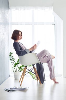 İyi görünümlü Bayan koltukta dergi okuma