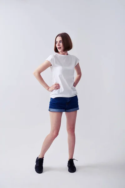 Hermosa mujer posando en pantalones cortos vaqueros y camiseta blanca —  Fotos de Stock