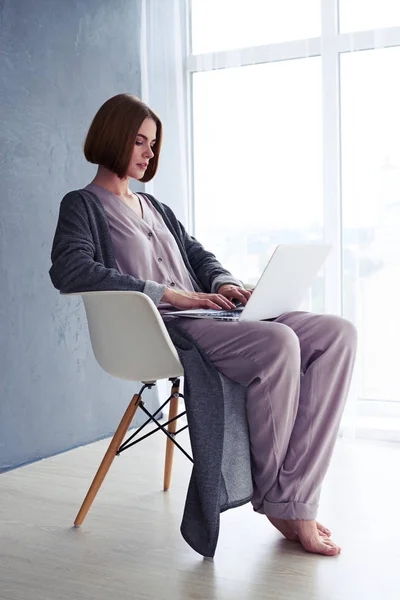 Ontspannen vrouw zittend op een stoel en surfen in laptop — Stockfoto