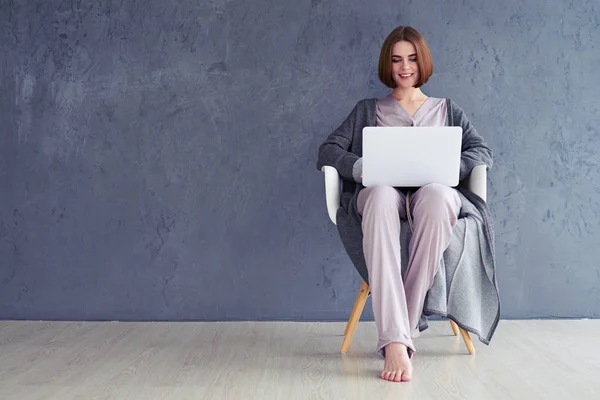 Frau entspannt auf Sessel sitzen und im Laptop surfen — Stockfoto