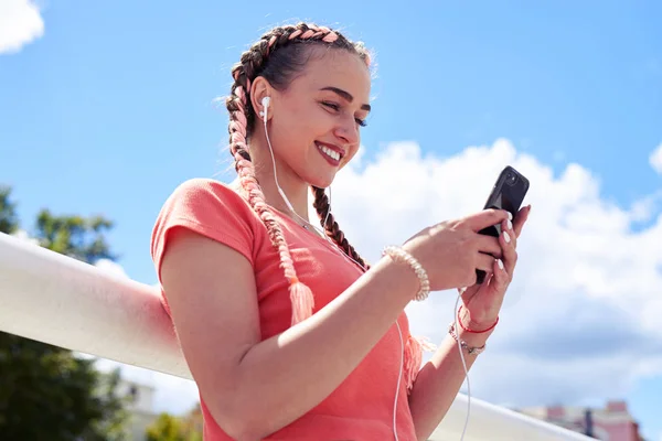 Graciösa blondin i hörlurar surfing i smartphone — Stockfoto