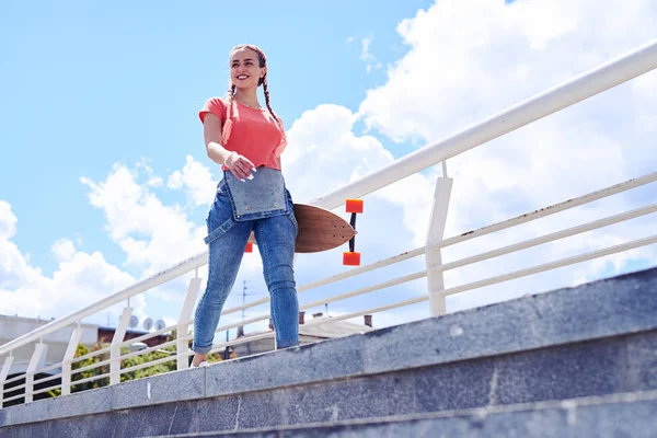 Bella femmina che cammina con lo skateboard in mano — Foto Stock