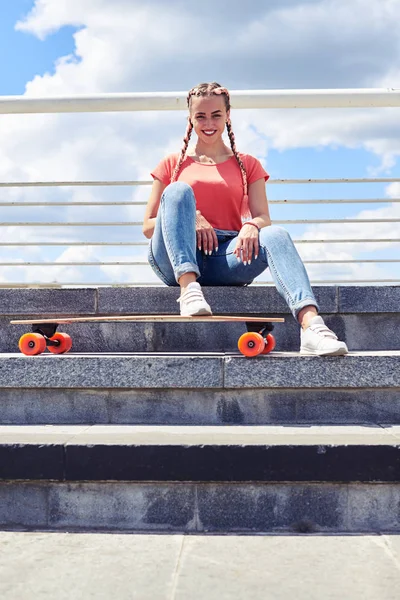 Agradável fêmea tendo descanso nas escadas depois de andar de skate — Fotografia de Stock