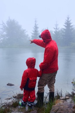 Baba oğul göl kenarında bir şeyler gösteriyor