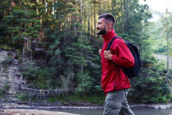 Smiling bearded man hiking along mountains river — Stock Photo, Image