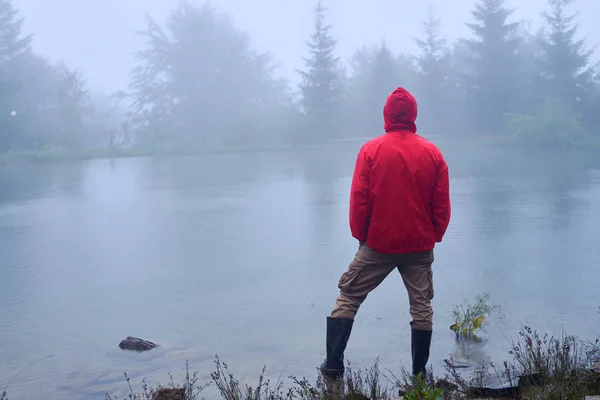 Muž s rukama v kapse při pohledu na jezero — Stock fotografie