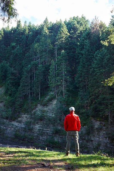 Man hiker in waterproof jacket admiring the cliff — Stock Photo, Image