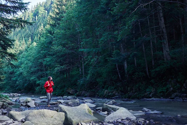 Male hiker with backpack walking along mountain river — Stock Photo, Image