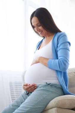 Hamile kadın kanepede otururken karın dokunmadan