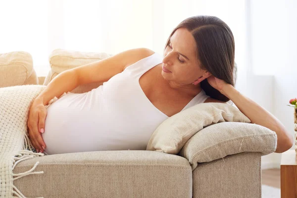 Pregnant woman lying on sofa under blanket — Stock Photo, Image