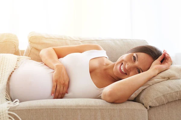 Sourire femme enceinte sous couverture — Photo