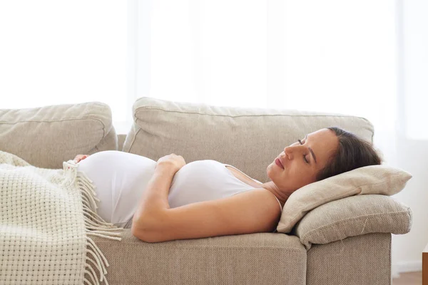 Tranquil woman embracing belly while sleeping on back — Stock Photo, Image