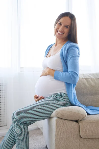 Mulher segurando barriga e olhando para a câmera — Fotografia de Stock