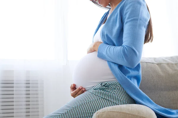 Woman expecting a baby holding hands on her belly — Stock Photo, Image