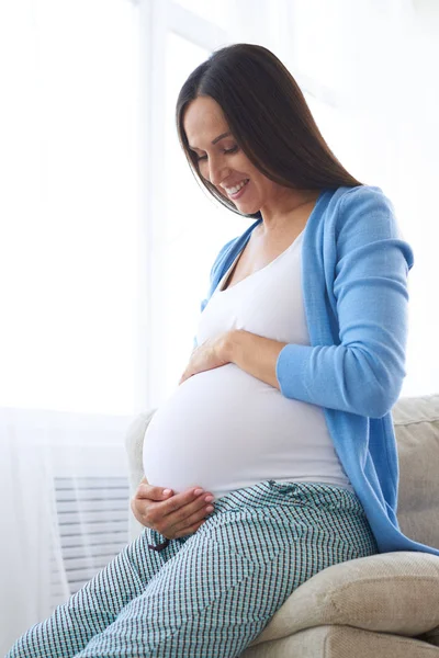 Hamile kadın kanepede otururken karın dokunmadan