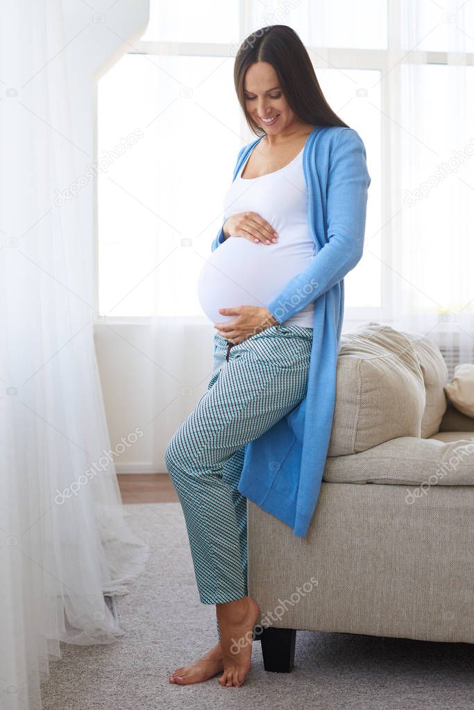 Positive pregnant woman looking at belly 