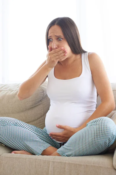 Pregnant young woman sitting on sofa and feeling sick — Stock Photo, Image