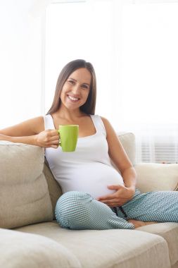 Kanepe üzerinde çay çekici hamile kadın