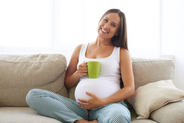 Schwangere sitzt mit Tasse Tee auf Sofa — Stockfoto