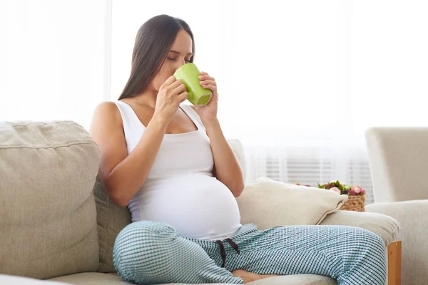Mujer embarazada satisfecha degustación de té de taza — Foto de Stock