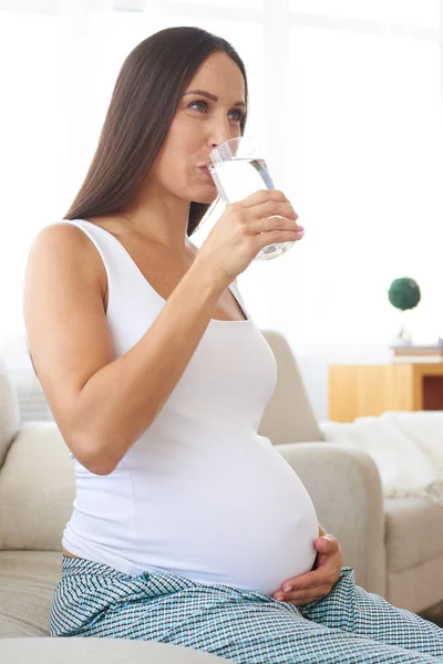 Positive pregnant woman drinking water from glass — Stock Photo, Image