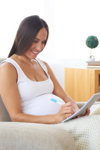 Όμορφος έγκυος γυναίκα κάνοντας σημειώσεις στο μπλοκ σε πολυθρόνα — Φωτογραφία Αρχείου