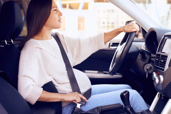 Pregnant woman driver in driver seat adjusts seat belt — Stock Photo, Image