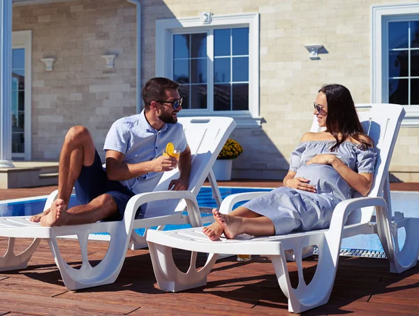 Ehepaar unterhält sich beim Ausruhen am Pool — Stockfoto