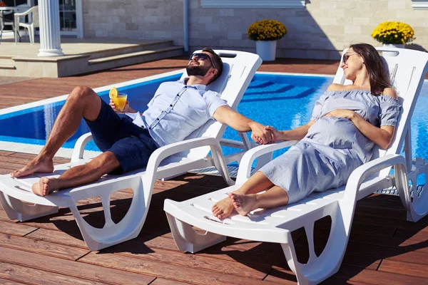 Entspanntes Paar hält Händchen am Pool vor dem Haus — Stockfoto