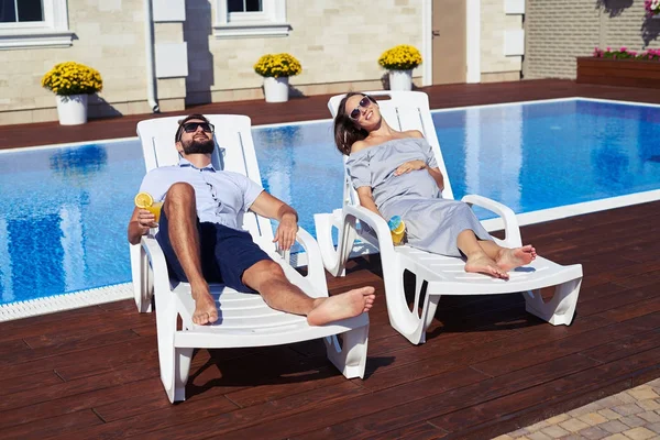 Glückliches Paar liegt auf Liegestühlen vor Haus mit Pool — Stockfoto