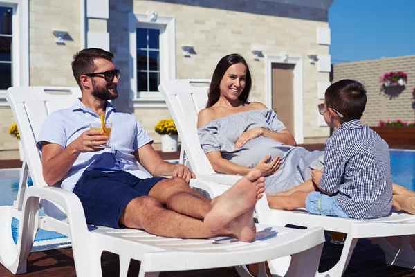 Vater, Sohn und schwangere Mutter ruhen sich vor Haus mit p aus — Stockfoto