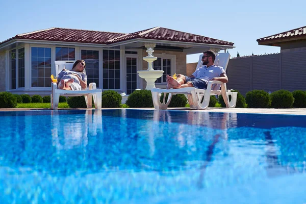 Modernes Paar bräunt sich unter der Sonne am Pool — Stockfoto