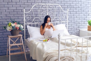 Hamile kadın yatakta çalışma ve having kahvaltı 