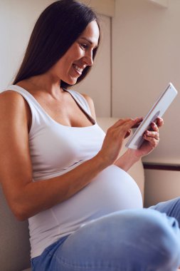 Rahat hamile kadın kanepe evde tablet ile dinlenme