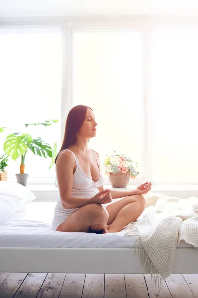 Mujer embarazada relajada haciendo meditación en el dormitorio —  Fotos de Stock