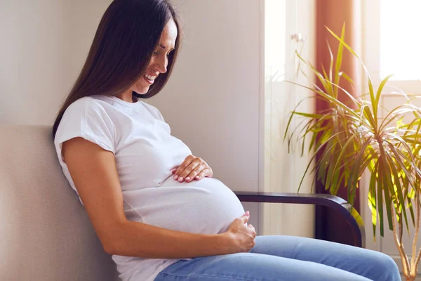 Bella donna incinta seduta sul divano a casa — Foto Stock