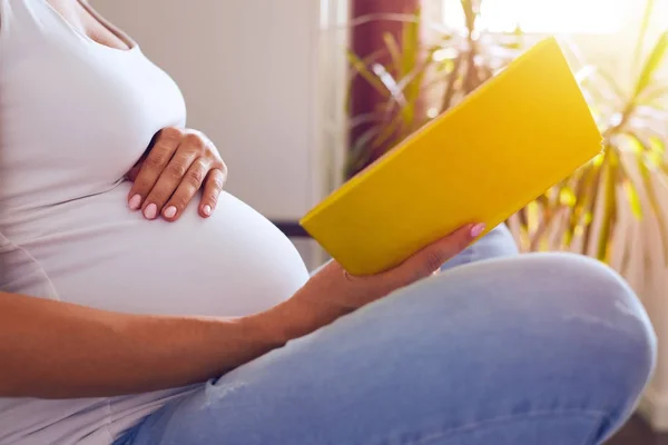 Werdende Mutter liest Buch auf Sofa — Stockfoto