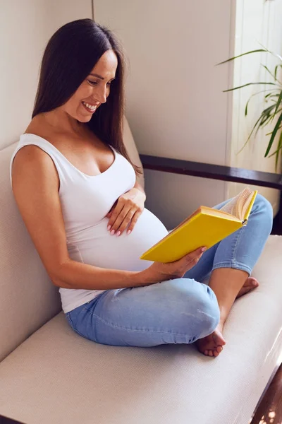 Jonge zwangere moeder thuis ontspannen en boek lezen — Stockfoto